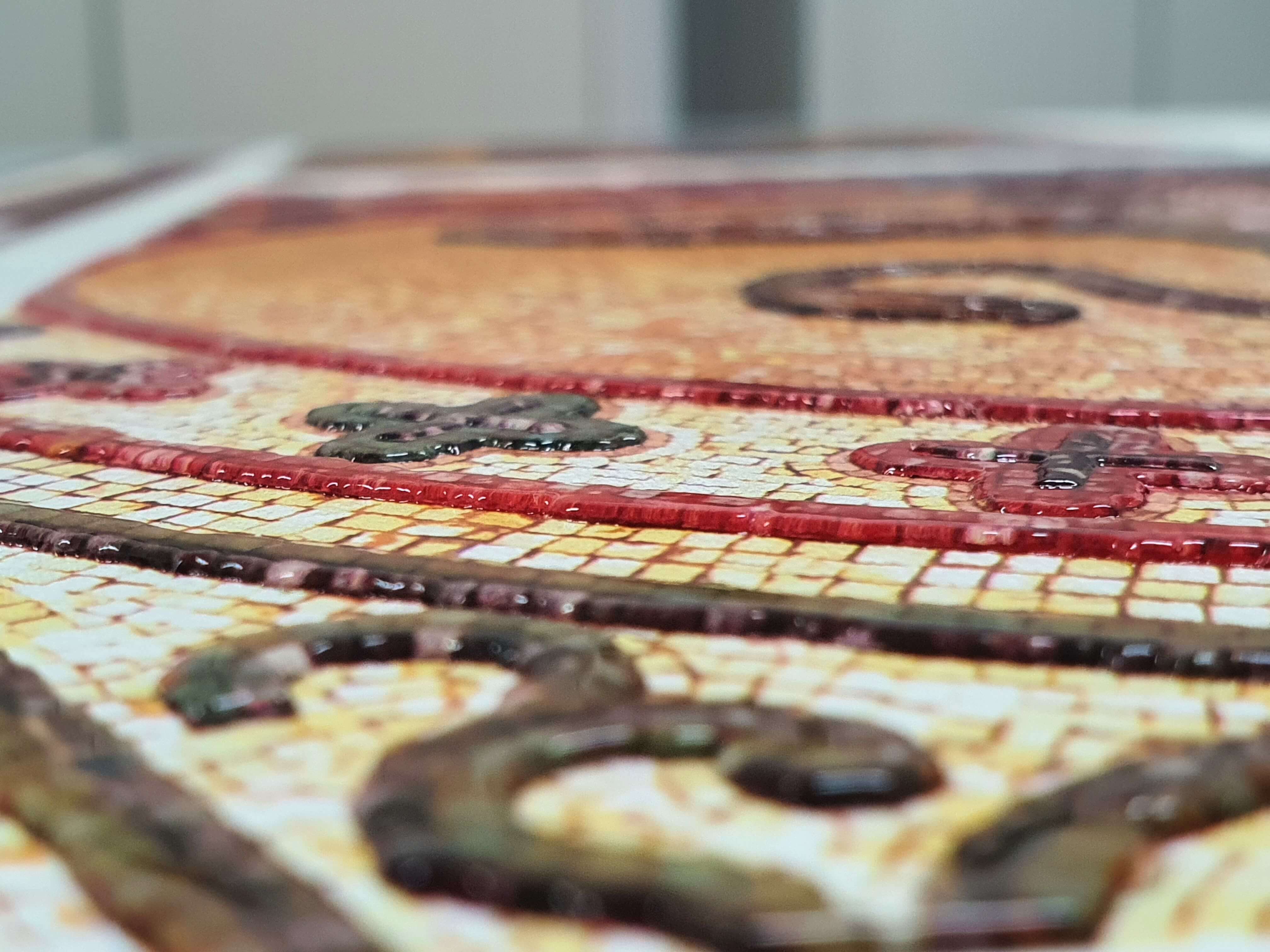 Inquadratura ravvicinata di una riproduzione tattile di un mosaico con contorni a rilievo per l'esplorazione sensoriale dei decori.