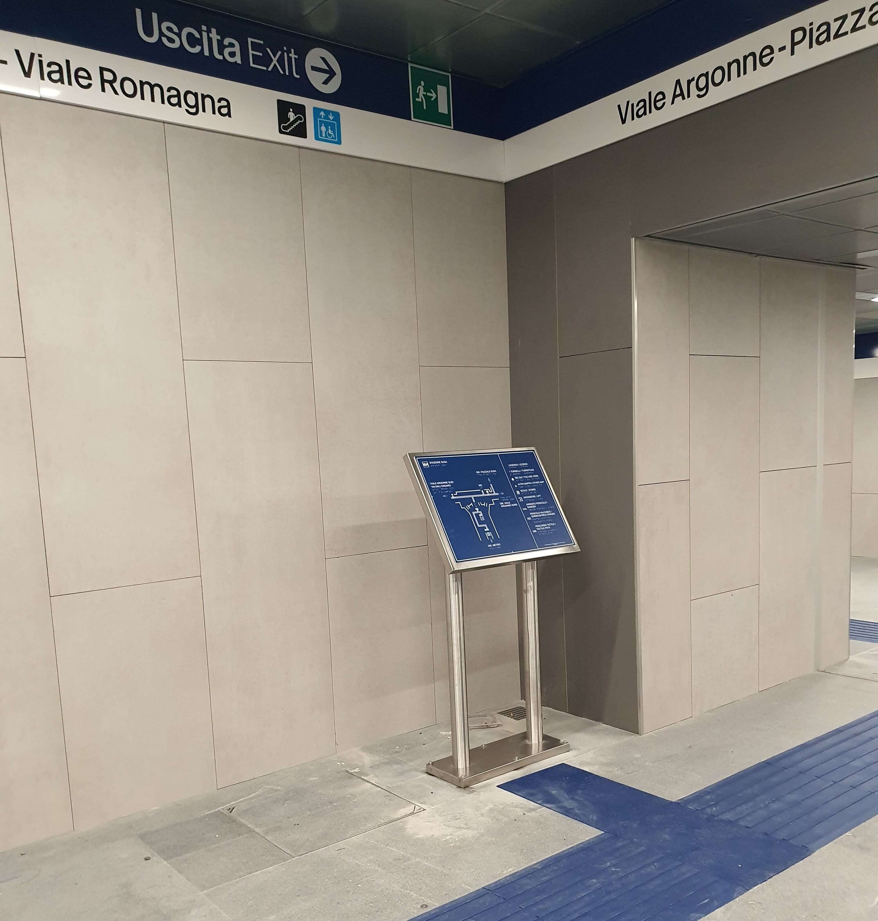 Leggio con mappa tattile della stazione metropolitana M4, posizionato strategicamente lungo il percorso podotattile blu per l'orientamento.