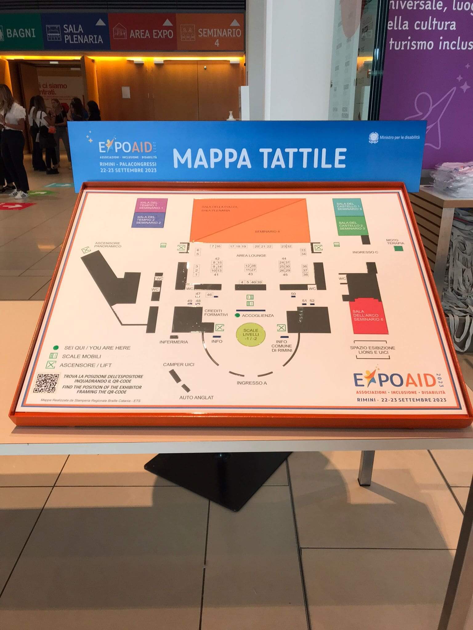 Mappa tattile ad alta leggibilità per l'evento EXPOAID 2023 a Rimini, con indicazione di percorsi, padiglioni e servizi.