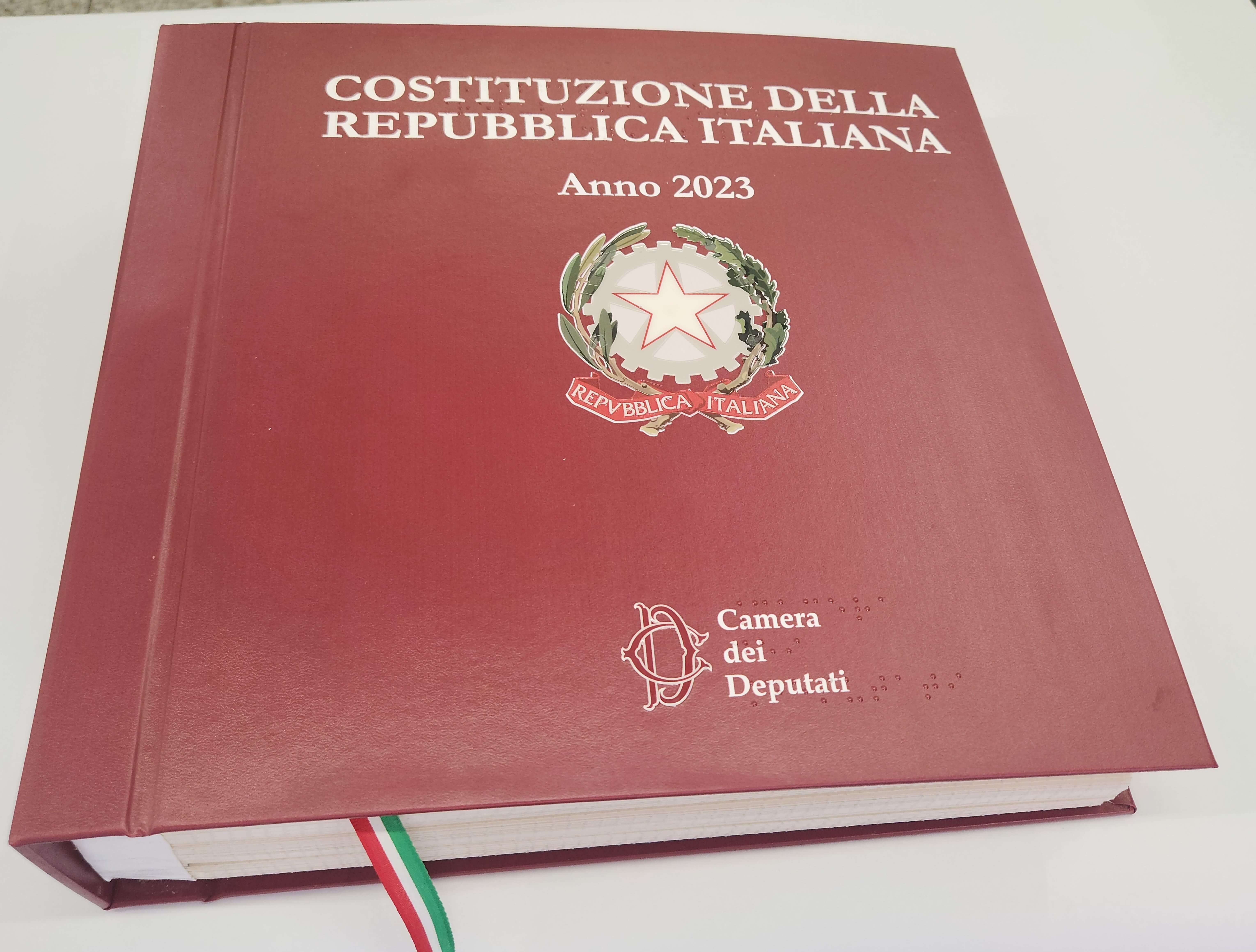 Copertina bordeaux della Costituzione Italiana 2023, edizione della Camera dei Deputati con scritte in Braille.