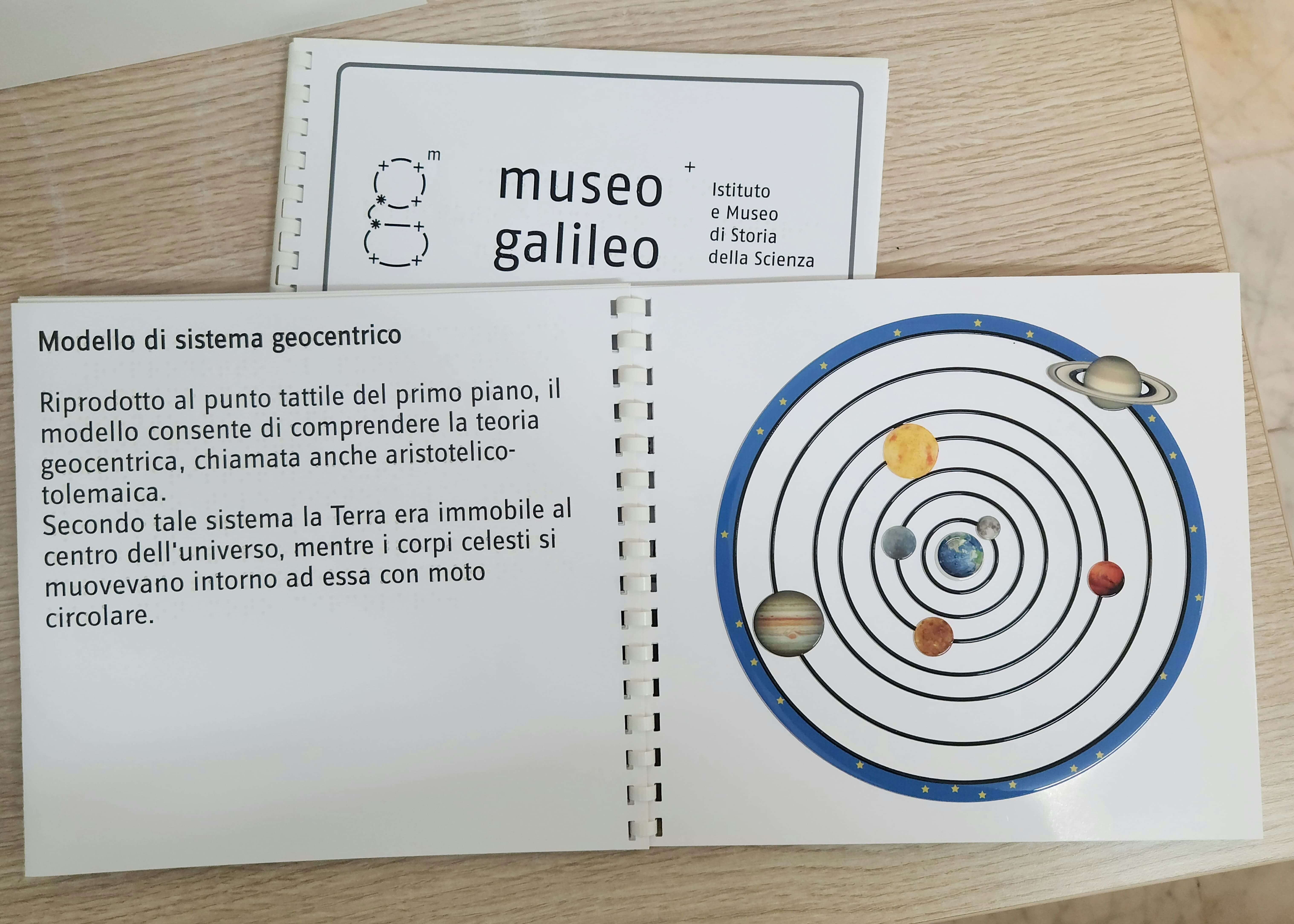 Illustrazione tattile del sistema geocentrico con orbite circolari e pianeti in rilievo per l'apprendimento sensoriale.