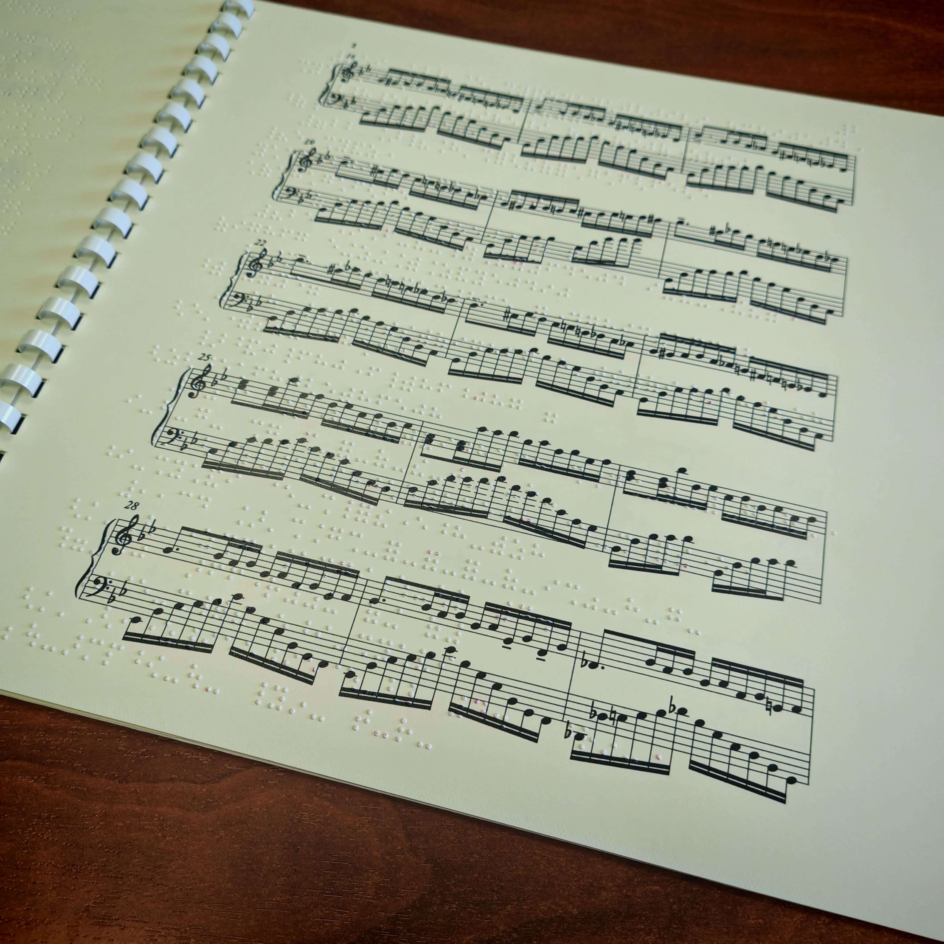 Pagina di uno spartito musicale per pianoforte con sovrapposizione di notazione Braille a rilievo per musicisti non vedenti.